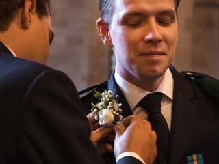 Vit ros f&auml;sts p&aring; brudgummens uniform inf&ouml;r vigseln &ndash; br&ouml;llopsfotograf Lund