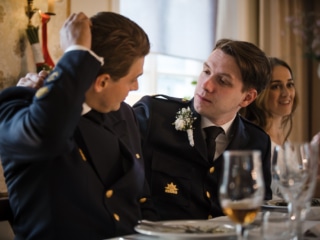 Brudgummen justerar en v&auml;ns uniform under festen &ndash; br&ouml;llopsfotograf Lund
