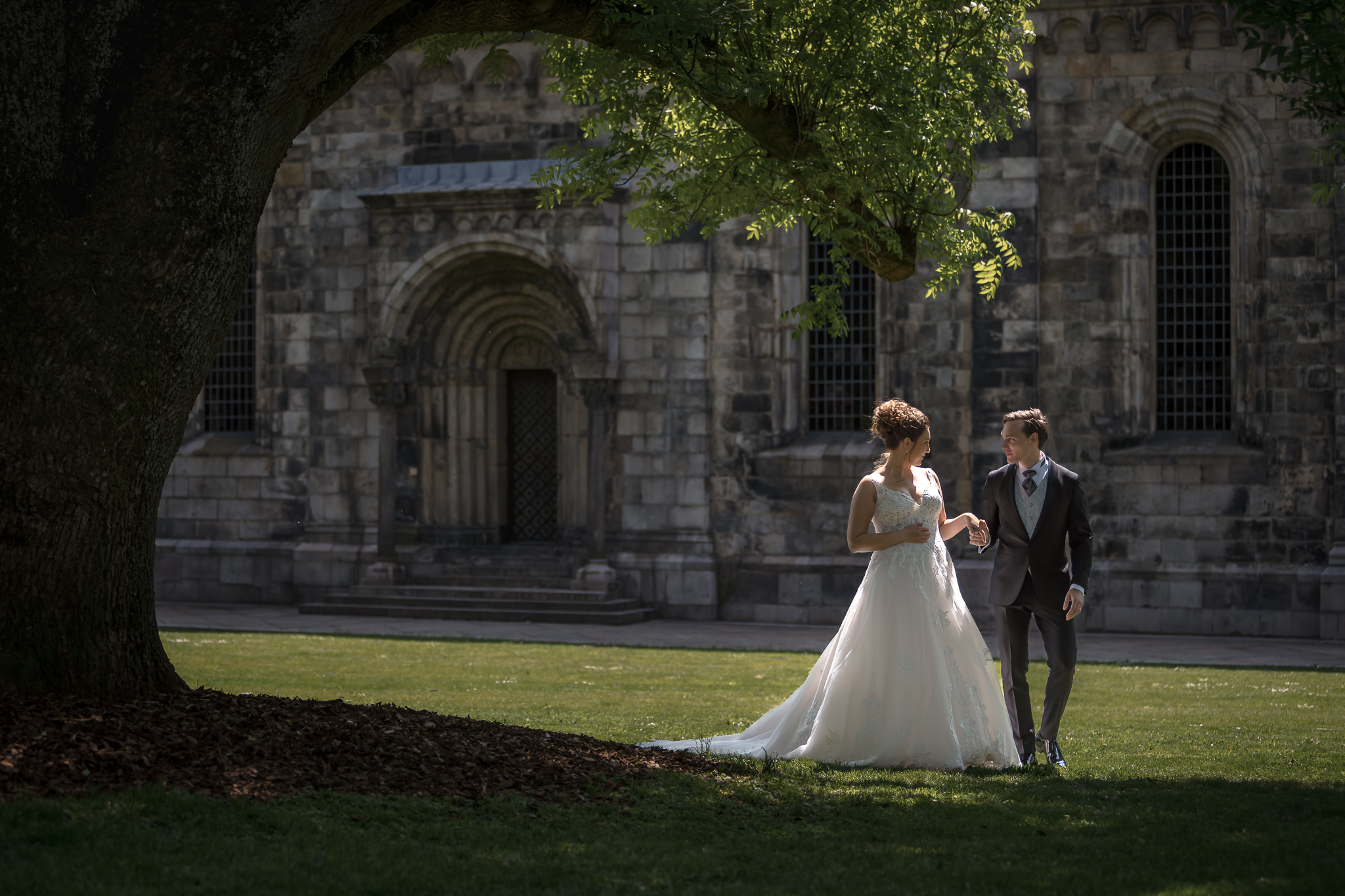 Promenad vid domkyrkan Brudpar promenerar vid Lunds domkyrka i vårsol – bröllopsfotograf Lund