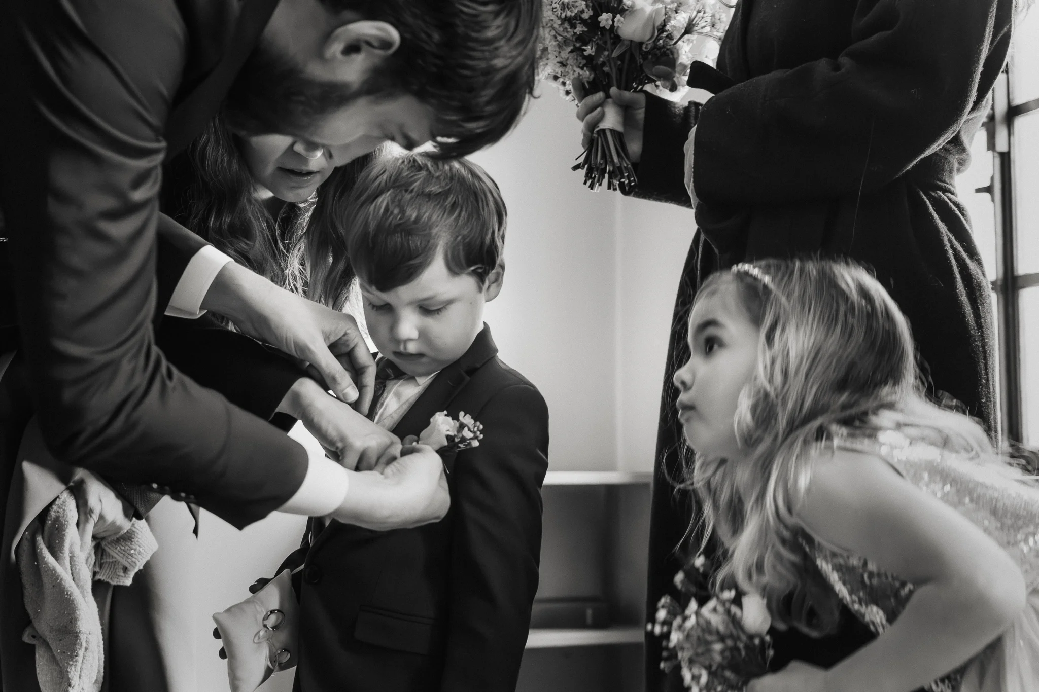 Boutonnièren fästs på pojken Barn får sin boutonnière fäst inför vigseln i Klosterkyrkan – bröllopsfotograf Lund