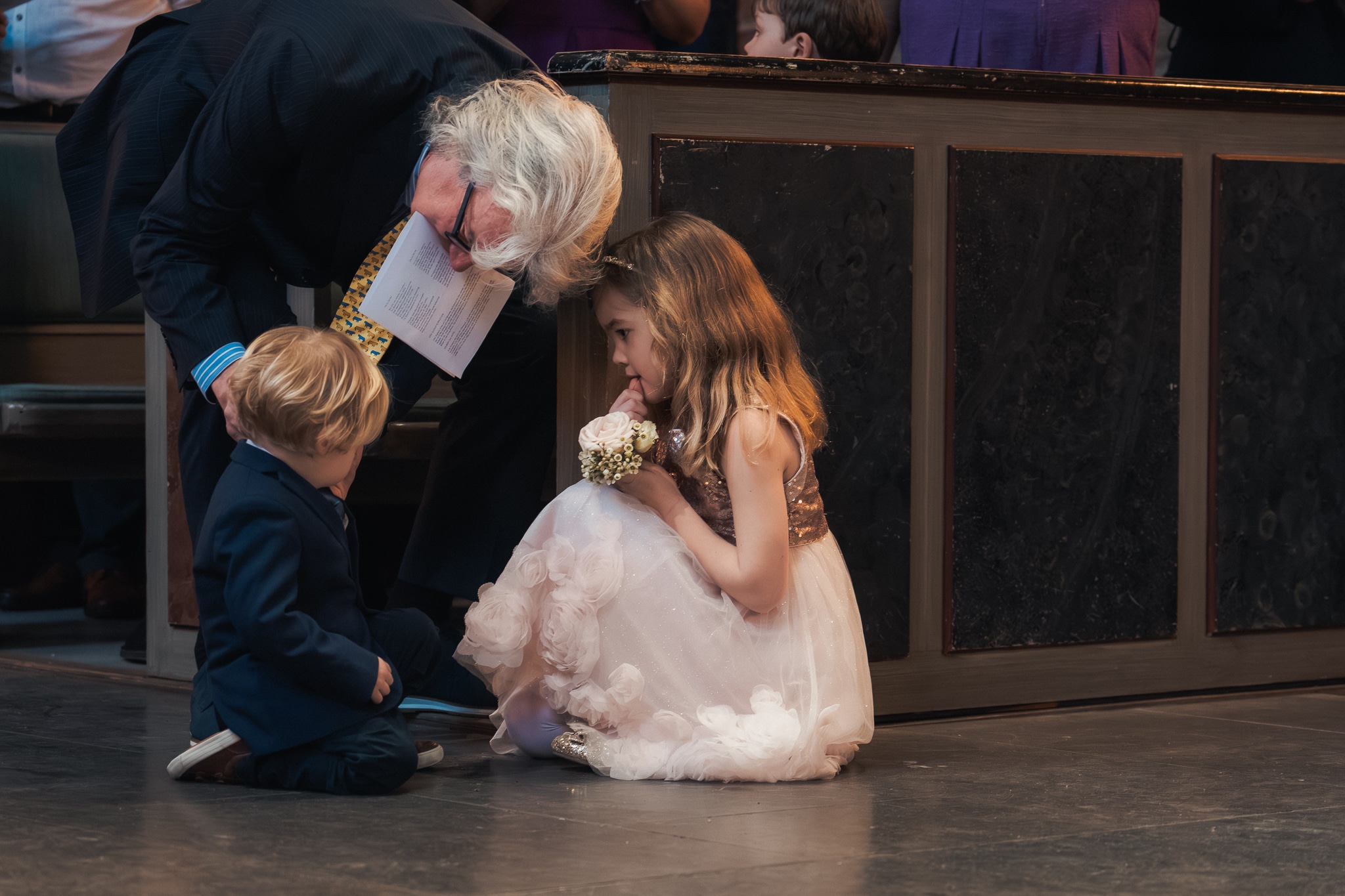 Ett samtal på golvet Gäst pratar med barnen på golvet under ceremonin i Klosterkyrkan – bröllopsfotograf Lund