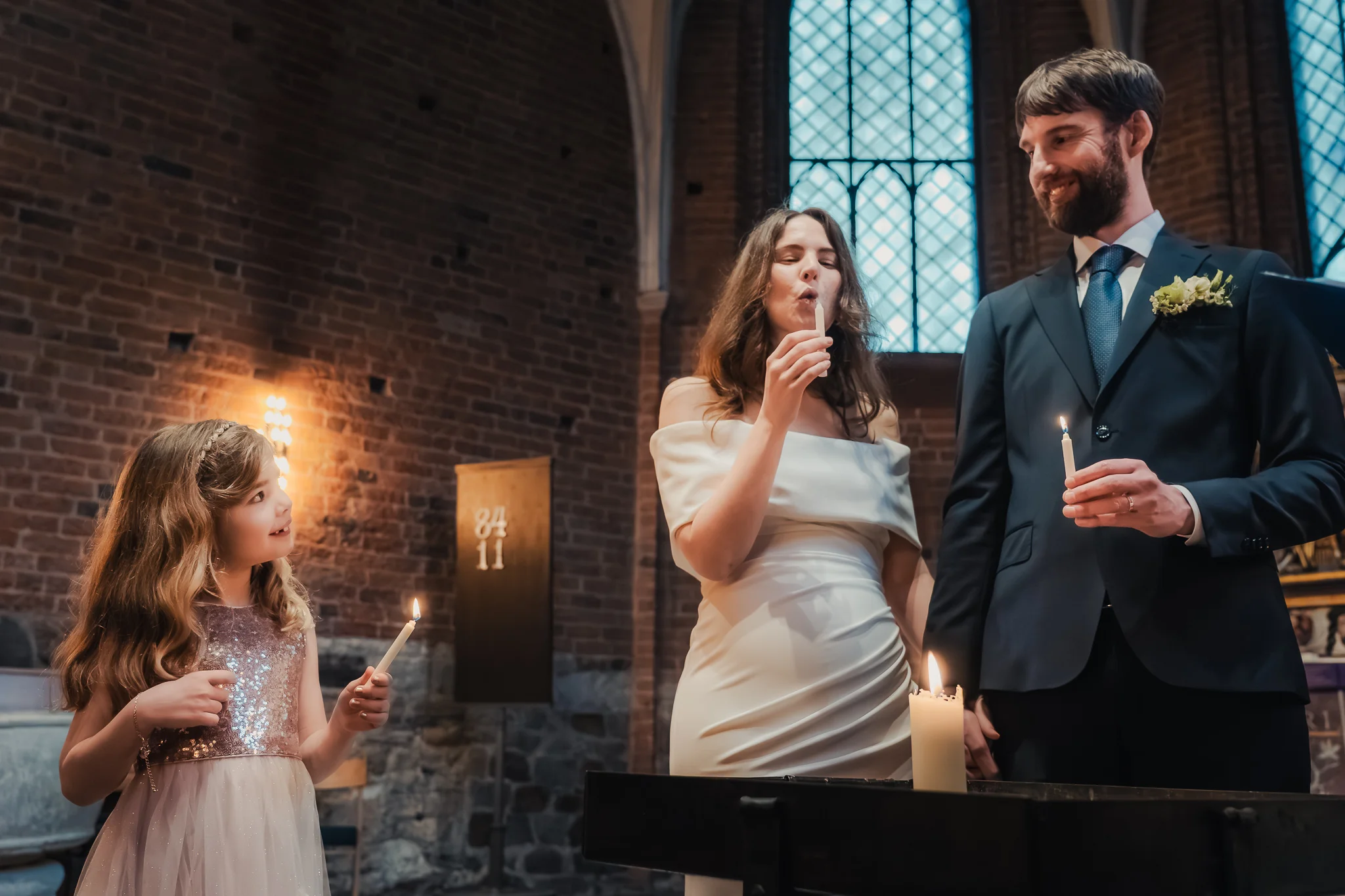 Ljuständningen Bruden tänder ljus under ceremonin i Klosterkyrkan i Lund – bröllopsfotograf Lund