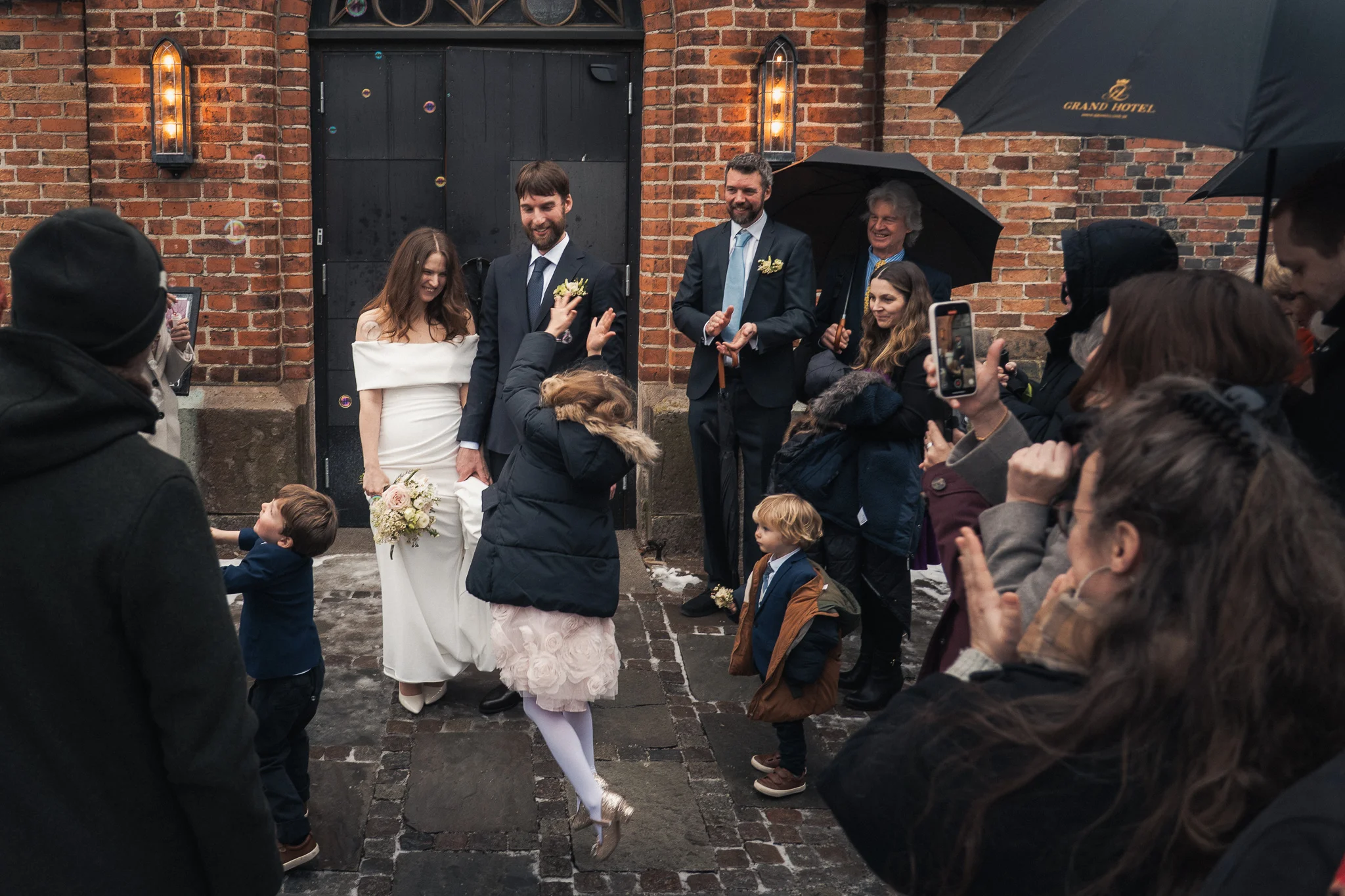 Utanför kyrkporten Gästerna gratulerar paret utanför Klosterkyrkan en vinterdag i Lund – bröllopsfotograf Lund