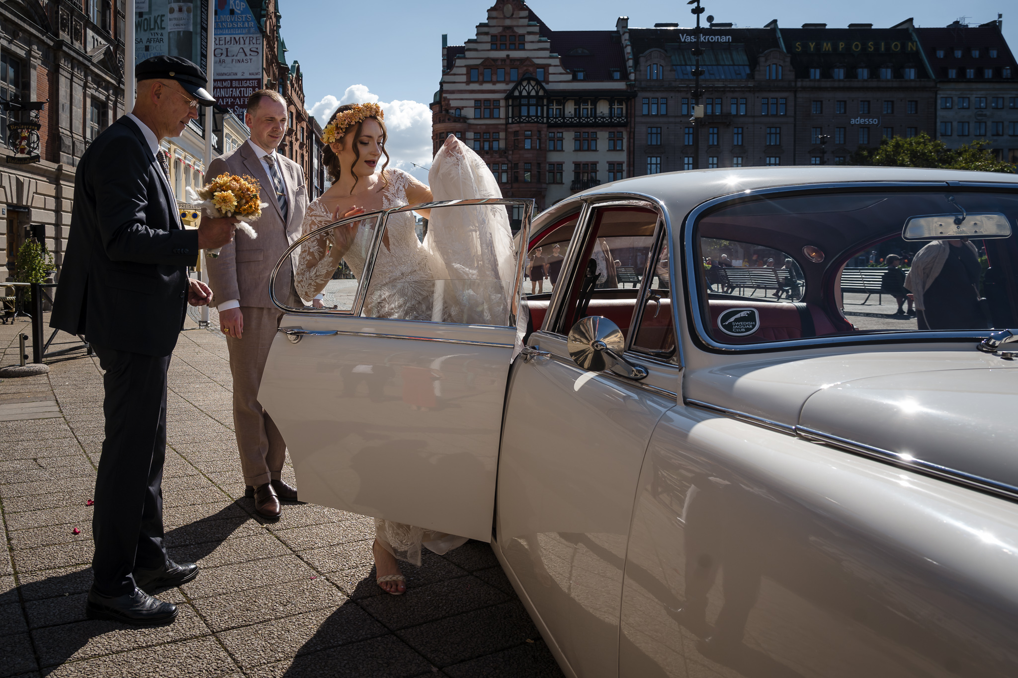 Bruden stiger in i Jaguaren Brud stiger in i vit Jaguar utanför Malmö Rådhus – bröllopsfotograf Malmö