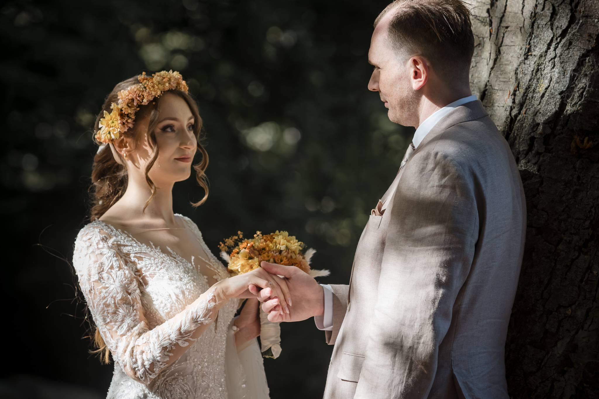 Porträtt vid trädstammen Porträtt av brudpar i solljus vid trädstam i Slottsparken, Malmö, bruden med blomsterkrans – bröllopsfotograf Malmö